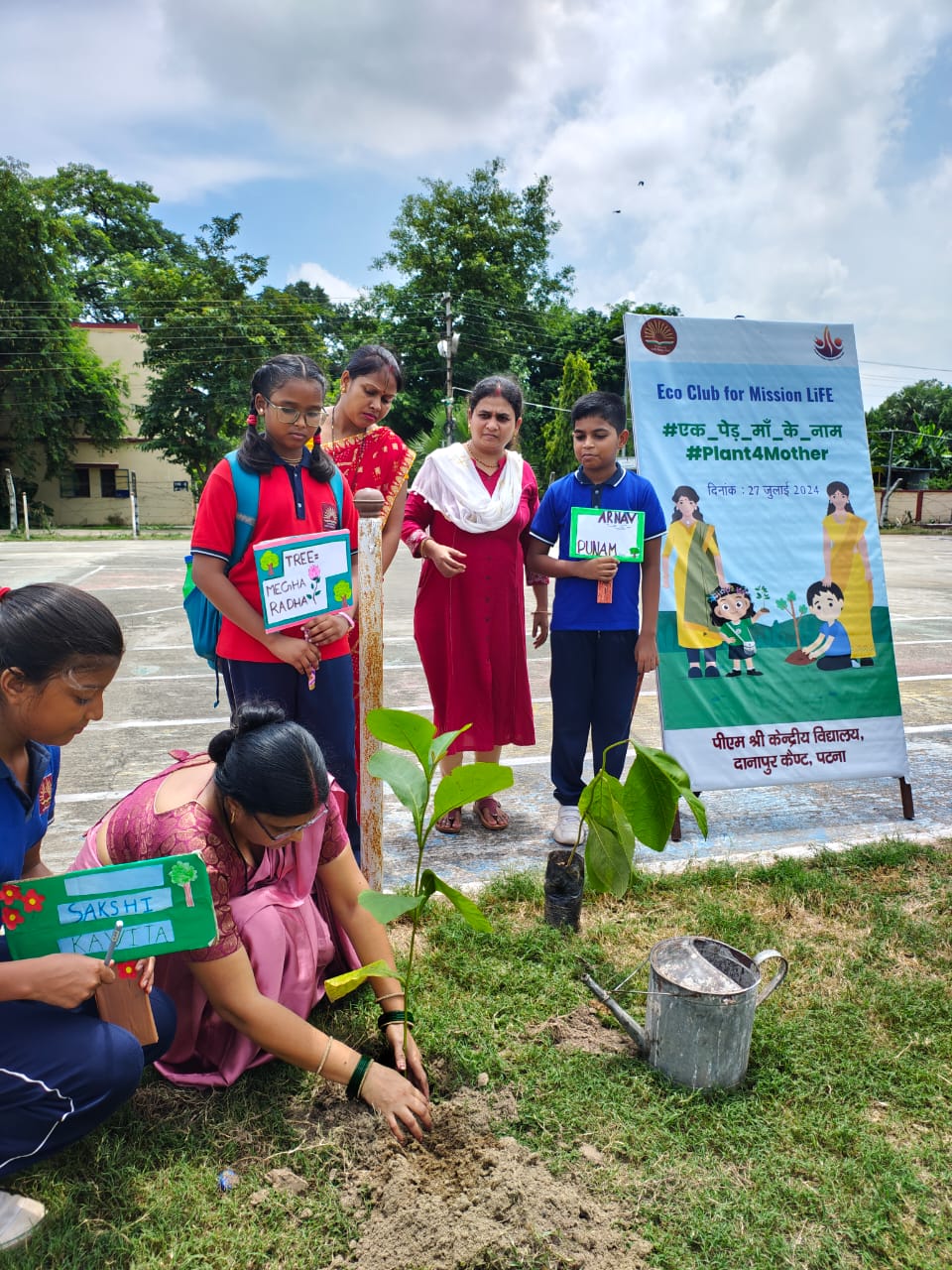 A student planting a sapling with teachers nearby